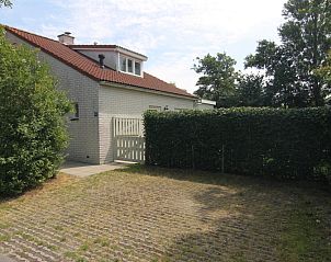 Das Ferienhaus D 618 in De Cocksdorp, Texel, bietet einen schnen Auenbereich mit grnen Hecken und einer einladenden Terrasse.