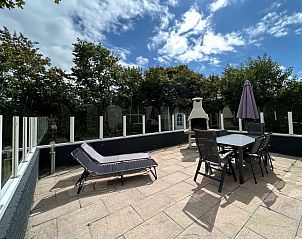 Geniet van het ruime terras van Vakantiehuis E 417 in De Cocksdorp, Texel, met comfortabele ligstoelen en een sfeervolle buitenhaard.