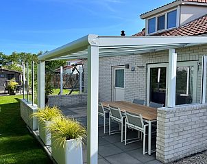Geniet van de zonnige veranda van Vakantiehuis D 728 in De Cocksdorp, Texel, met een ruim terras en uitzicht op de groene omgeving.