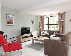 Gezellige woonkamer van Vakantiehuis D 485 in De Cocksdorp, Texel, met comfortabele banken en een groot raam dat uitzicht biedt op de natuur.