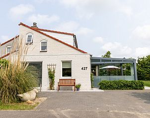Vakantiehuis D 427 in De Cocksdorp, Texel, biedt een charmante buitenkant en een uitnodigende veranda voor een ontspannen verblijf op de Waddeneilanden.