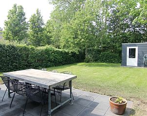 Ontspan op het terras van Vakantiehuis A 351 in De Cocksdorp, Texel, met uitzicht op een groene tuin en rustige natuur.