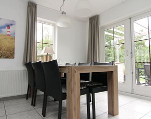 Gezellige eetkamer in Vakantiehuis D 533, De Cocksdorp, Texel, met uitzicht op de tuin via grote ramen, ideaal voor een ontspannen verblijf.