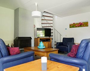 Gezellige woonkamer van Vakantiehuis D 479 in De Cocksdorp, Texel. Comfortabele zithoek met open haard en trap naar boven.