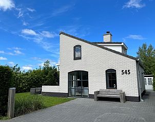 Vakantiehuis E 545 in De Cocksdorp, Texel, met charmante witte gevel en groene omgeving, ideaal voor een ontspannen verblijf op de Waddeneilanden.