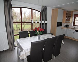 Gezellige eetkamer in Vakantiehuis E 407, De Cocksdorp, Texel met uitzicht op tuin en moderne keuken, ideaal voor familievakanties op de Waddeneilanden.