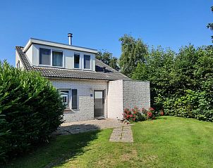 Vakantiehuis F 654 in De Cocksdorp, Texel, omgeven door groene tuin en blauwe lucht, ideaal voor een ontspannen verblijf op de Waddeneilanden.