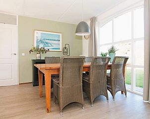Cozy dining area in Holiday Home F 681, De Cocksdorp, Texel overlooking the garden through large windows.