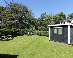 Ruime tuin van Vakantiehuis F 776 in De Cocksdorp, Texel, met groen gazon en houten schuur, ideaal voor ontspanning op de Waddeneilanden.
