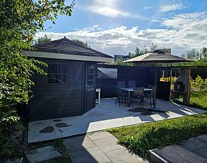 Geniet van de zon op het terras van Vakantiehuis E 525 in De Cocksdorp, Texel, met comfortabele zitruimte en groene omgeving.