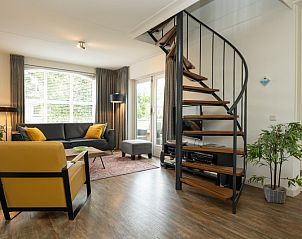 Gezellige woonkamer in Vakantiehuis E 541, De Cocksdorp, Texel met moderne inrichting en spiraaltrap, ideaal voor een ontspannen verblijf.