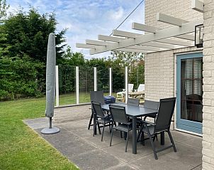 Gezellige terras van Vakantiehuis E 501 in De Cocksdorp, Texel met moderne zitruimte en groene tuin voor ultiem buitenplezier.