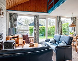 Gezellige woonkamer van Vakantiehuis Slufterhoek 110 in De Cocksdorp, Texel met uitzicht op groene tuin en comfortabele zithoek.