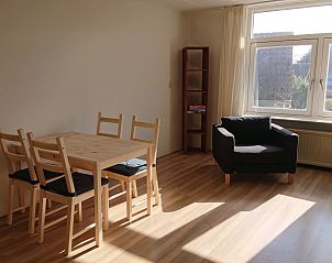 Helles Interieur des Ferienhauses Kikkerpoel in De Cocksdorp, Texel mit Holzboden und bequemem Sessel.