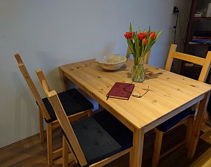 Esstisch im Ferienhaus Kikkerpoel, De Cocksdorp, Texel mit Tulpen und Notizbuch, ideal fr entspannte Mahlzeiten.