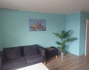 Gerumiges Wohnzimmer im Ferienhaus Kikkerpoel, De Cocksdorp, Texel mit Sofa, Pflanzen und Wanddekoration.