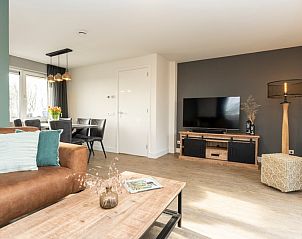 Moderne woonkamer in Duinoord Texel vakantiehuis, De Cocksdorp, met flatscreen-tv en houten meubels.