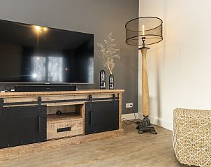 Gezellige tv-hoek in Duinoord Texel vakantiehuis, De Cocksdorp, met stijlvolle lamp en rustieke kast.