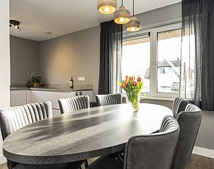 Eetgedeelte in Duinoord Texel vakantiehuis, De Cocksdorp, met grote tafel en bloemen op tafel.