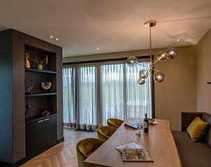 Ruime eetkamer in 6 persoons vakantiewoning, De Cocksdorp, Texel met houten tafel en moderne verlichting.