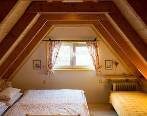 Sfeervolle slaapkamer in vakantiehuis Wind en Zee, De Koog, Texel, met houten balken en veel licht.