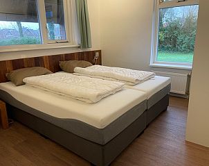 Attractive bedroom in vacation home Vogelmient 55, De Koog, Texel, with comfortable double bed and views of the green surroundings.