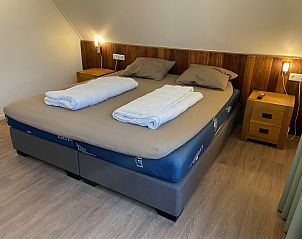 Cozy bedroom in vacation home Vogelmient 55, De Koog, Texel with comfortable double bed and warm wooden accents.