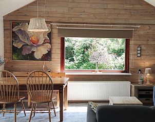 Gezellige binnenruimte van Bungalowpark 't Hoogelandt - Carpe Diem Texel in De Koog, met houten interieur en uitzicht op de groene natuur.