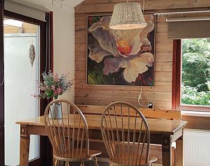 Gezellige eetruimte in Bungalowpark 't Hoogelandt - Carpe Diem Texel, De Koog. Vakantiehuis met houten interieur en kunst aan de muur.