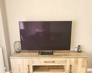 Stijlvolle woonkamer van Motel Texel Appartement (1N) in De Koog, Texel met moderne tv en houten meubel voor een ontspannen verblijf.