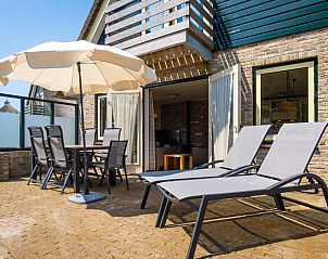 Sunny terrace of Villa, De Koog, Texel with deck chairs and parasol for ultimate outdoor fun on the Wadden Islands.