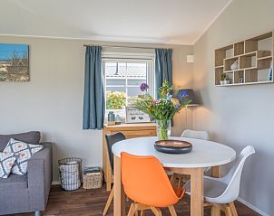 Eetgedeelte in Chalet Bregkoog 227, Chaletpark Bregkoog, De Koog, Texel met kleurrijke stoelen en een stijlvolle tafel.