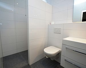 Moderne badkamer in Epelaan 31 vakantiehuis, De Koog, Texel, met strakke witte tegels en toilet.
