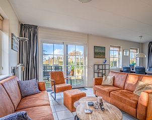 Lichte woonkamer met schuifdeuren naar het terras in vakantiehuis Maaikeduinweg 13, De Koog, Texel, perfect voor een zonnige dag.