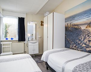 Slaapkamer in Bungalow 9708, De Koog, Texel met tweepersoonsbedden en stranddecor.