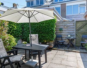 Priv tuin van Bungalow 9708, De Koog, Texel met groene omheining en comfortabele zitplaatsen.