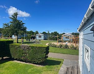 Chalet type 3 in De Koog, Texel biedt een prachtig uitzicht op de groene omgeving en speeltuin, ideaal voor een ontspannen vakantie.