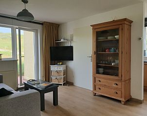 Gerumiges Wohnzimmer von De Duinpan - Duinhuisje Texel in De Koog, Texel, mit Holzschrank und Fernseher.