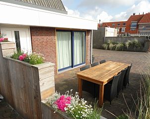 Gezellig terras bij Vakantiehuis Koogerduin in De Koog, Texel, met houten tafel en kleurrijke bloemen.