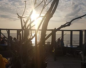Zonsondergang bij terras in De Koog, Texel. Genieten van het uitzicht op zee nabij vakantiehuis De Anemoon.