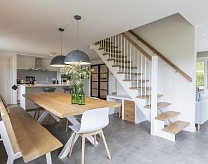 Moderne eetkamer in Buitenduin vakantiehuis, De Koog, Texel met houten tafel en open keuken.