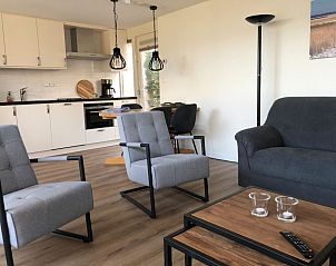 't Buitenhuisje in De Koog, Texel biedt een moderne woonkamer met comfortabele stoelen en een gezellige sfeer in dit vakantiehuis.