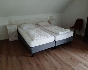 Hoofdslaapkamer in Aan de Maaikeduinen appartement, De Koog, Texel met tweepersoonsbed en houten vloer.