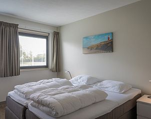 Tweede slaapkamer in Orchismient 24, De Koog, Texel met uitzicht op de tuin en sfeervolle decoratie.