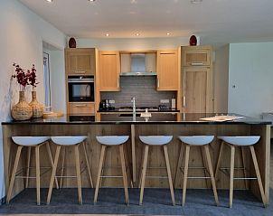 Moderne keuken in Villa Duyncoogh, een vakantiehuis in De Koog, Texel, met houten elementen en een uitnodigende bar op de Waddeneilanden.