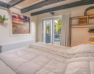 Slaapkamer met stijlvol interieur en uitzicht op de tuin in Appartement Zee van Tijd, De Koog, Texel.