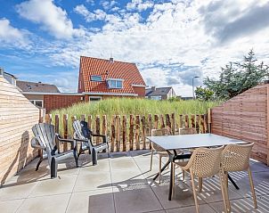 Zonnig terras van De Duinroos in De Koog, Texel met zitgelegenheid en uitzicht op duinen.