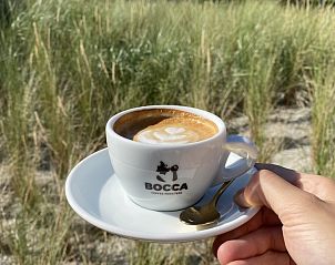 Genieten van koffie op het terras van De Duinroos, De Koog, Texel met duinen op de achtergrond.