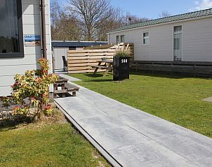 Chalet Bregkoog 208 in De Koog, Texel, met een ruim terras en een groene omgeving voor een ontspannen vakantie.