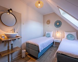 Ruime tweepersoonsslaapkamer in De Strandleeuwerik, Texel, met moderne wastafel, grote ramen en sfeervolle verlichting.